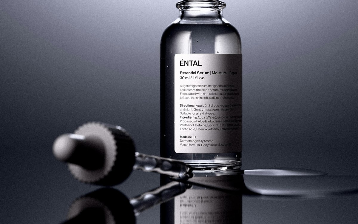 Cosmetic serum bottle and dropper on a reflective surface